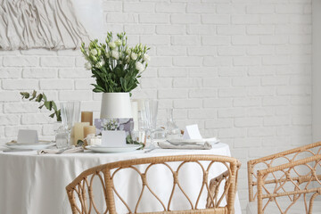 Beautiful table setting with eustoma flowers and candles for wedding celebration in room