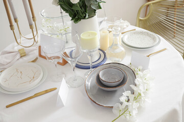 Beautiful table setting with white flowers and candles for wedding celebration in room, closeup