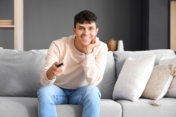 Fototapeta premium Young man watching TV on sofa at home