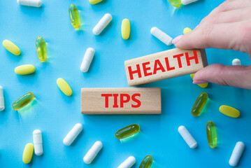 Health Tips symbol. Wooden blocks with words Health Tips. Beautiful blue background with pills. Doctor hand. Medicine and Health Tips concept. Copy space.