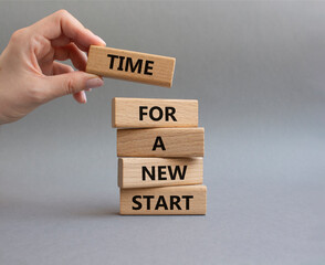 Time for a new start symbol. Wooden blocks with words Time for a new start. Beautiful grey background. Businessman hand. Business and Time for a new start concept. Copy space.