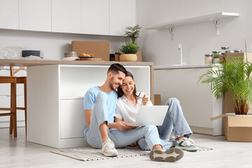 Young couple with laptop video chatting in kitchen on moving day