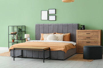 Comfortable bed, pillows and wooden chest of drawers in stylish bedroom