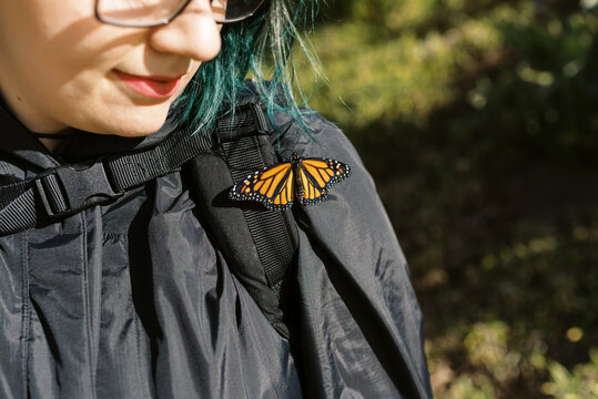 monarch butterfly on woman's jacket on sunny day