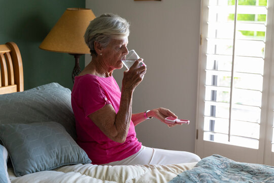 Woman Senior taking supplement pill drinking water in morning