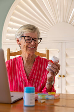 Senior hold prescription pill bottle while online  refill e-commerce 