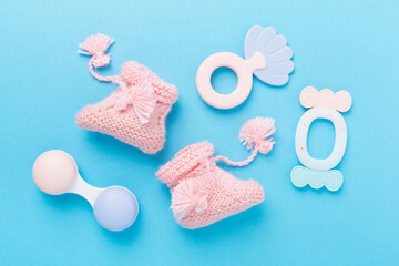 Pink baby booties and rattles on color background, top view