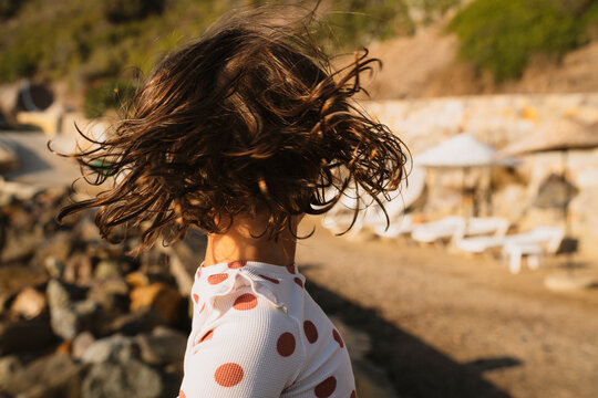 Little girl at the beach, turning her head, throwing her hair