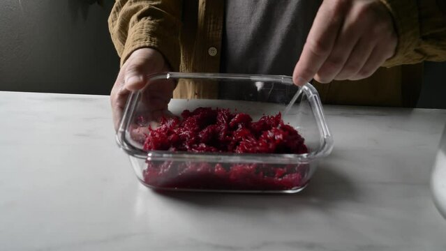 man stirring boiled beets in glass container in kitchen