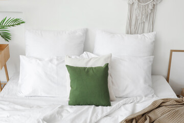 Cozy bed with soft pillows in light bedroom, closeup