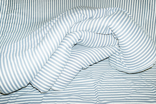 Bed with striped pattern duvet, mattress, pillow with hard flashlight