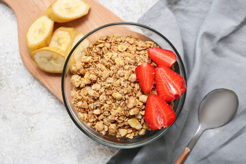 Wooden cutting board, bowl with tasty granola, banana and berries on grunge background, closeup