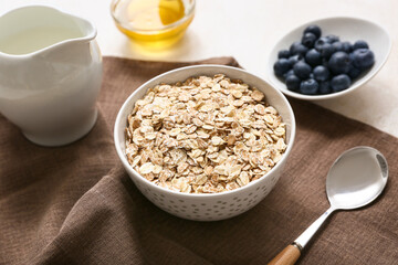 Napkin, bowl with raw oatmeal and berries on light background, closeup