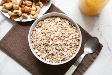 Napkin, nuts and bowl with raw oatmeal on marble background, closeup
