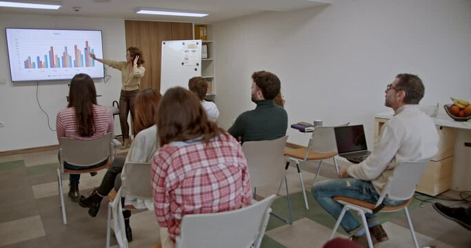 During a business seminar in a classroom setting, a group of workers is focused on skill development, actively participating to enhance their professional abilities and knowledge.