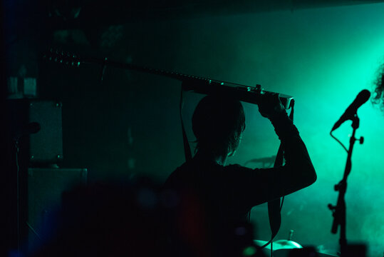 Silhouette of man with guitar over his head