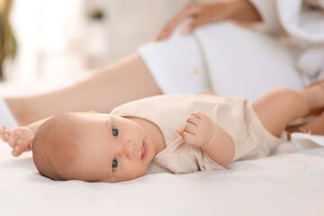 Beautiful young woman in bathrobe with her baby lying on bed at home, closeup