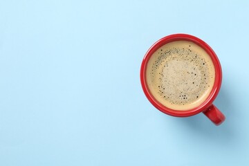 Tasty coffee in cup on light blue background, top view. Space for text