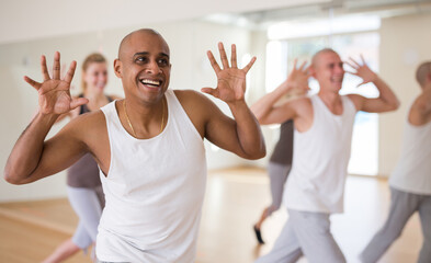 Portrait of latin american adult dancer practicing dynamic synchronous choreography with group in...