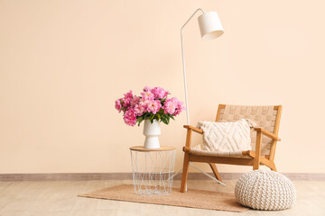 Vase with peonies flowers on coffee table near armchair in stylish living room
