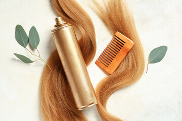 Hair spray with strands and comb on light background