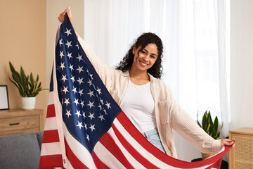 Beautiful young happy African-American woman with USA flag at home