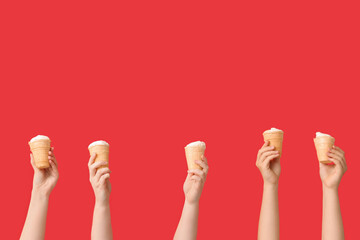 Female hands with sweet ice-cream in waffle cups on red background