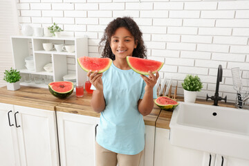 Cute African-American girl with slices of sweet watermelon in kitchen