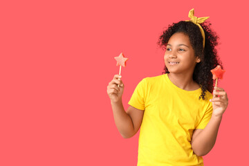 Cute African-American girl holding sticks with sweet watermelon in shape of stars on red background