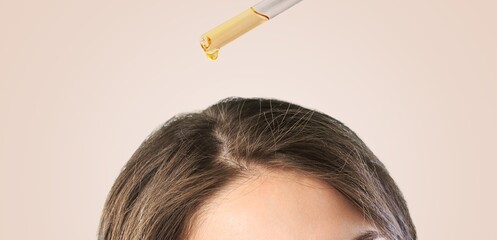 A young woman hand applies oil drop to hair