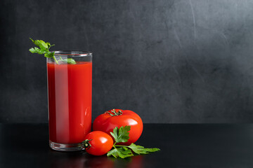 Delicious tomato juice on black background. Vegetable drink for vegan and healthy eating.