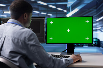 African american man in data center using green screen computer to check for server performance...