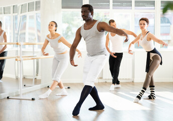 Group of multinational men and women rehearsing ballet moves in dance studio