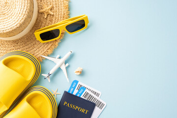 Flat lay of summer travel items including hat, yellow sandals, sunglasses, passport, and airplane...
