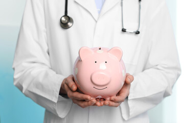Doctor with piggy bank in hospital, closeup
