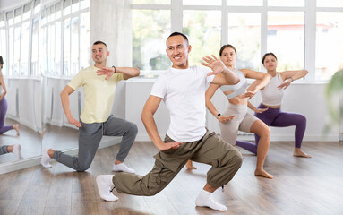 Fototapeta premium Emotional sporty young Asian dancer rehearsing modern krump dance moves during group workout in studio