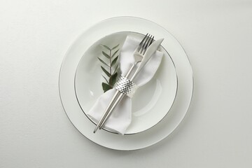 Stylish setting with cutlery and napkin on white textured table, top view