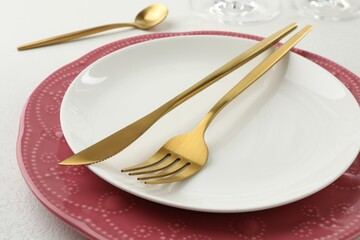 Stylish setting with cutlery and plates on white textured table, closeup