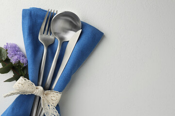 Stylish setting with cutlery and napkin on white textured table, top view. Space for text