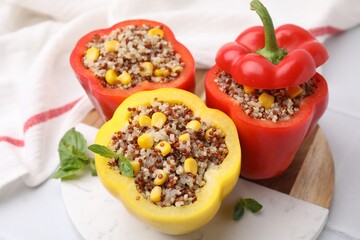 Quinoa stuffed bell peppers and basil on white table, closeup