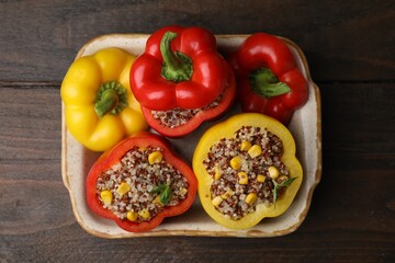 Quinoa stuffed bell peppers and basil in baking dish on wooden table, top view