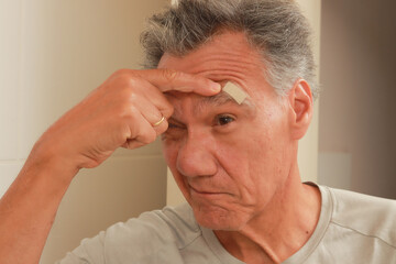 Obraz premium Band Aid on the brow of a man’s face to cover his wound