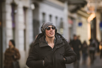 Fototapeta premium Young Man in the Winter City Streets with Headphones
