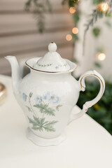 Floral white teapot with gold trim on table