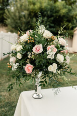 Elegant floral arrangement with pink and white roses on a table outdoors