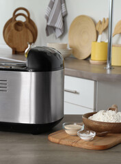 Breadmaker and products on wooden table in kitchen
