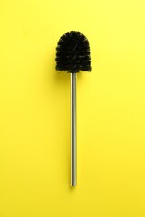 Toilet brush on yellow background, top view