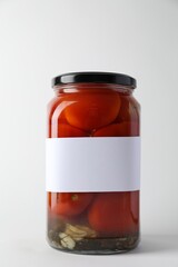 Tasty pickled tomatoes in jar on light background