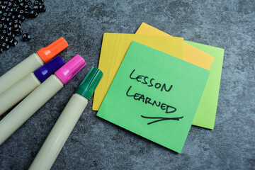 Concept of Lesson Learned write on sticky notes isolated on Wooden Table.