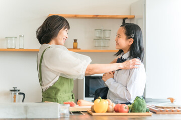 キッチンで料理をする母親と会話する制服姿の娘・子供・女の子
